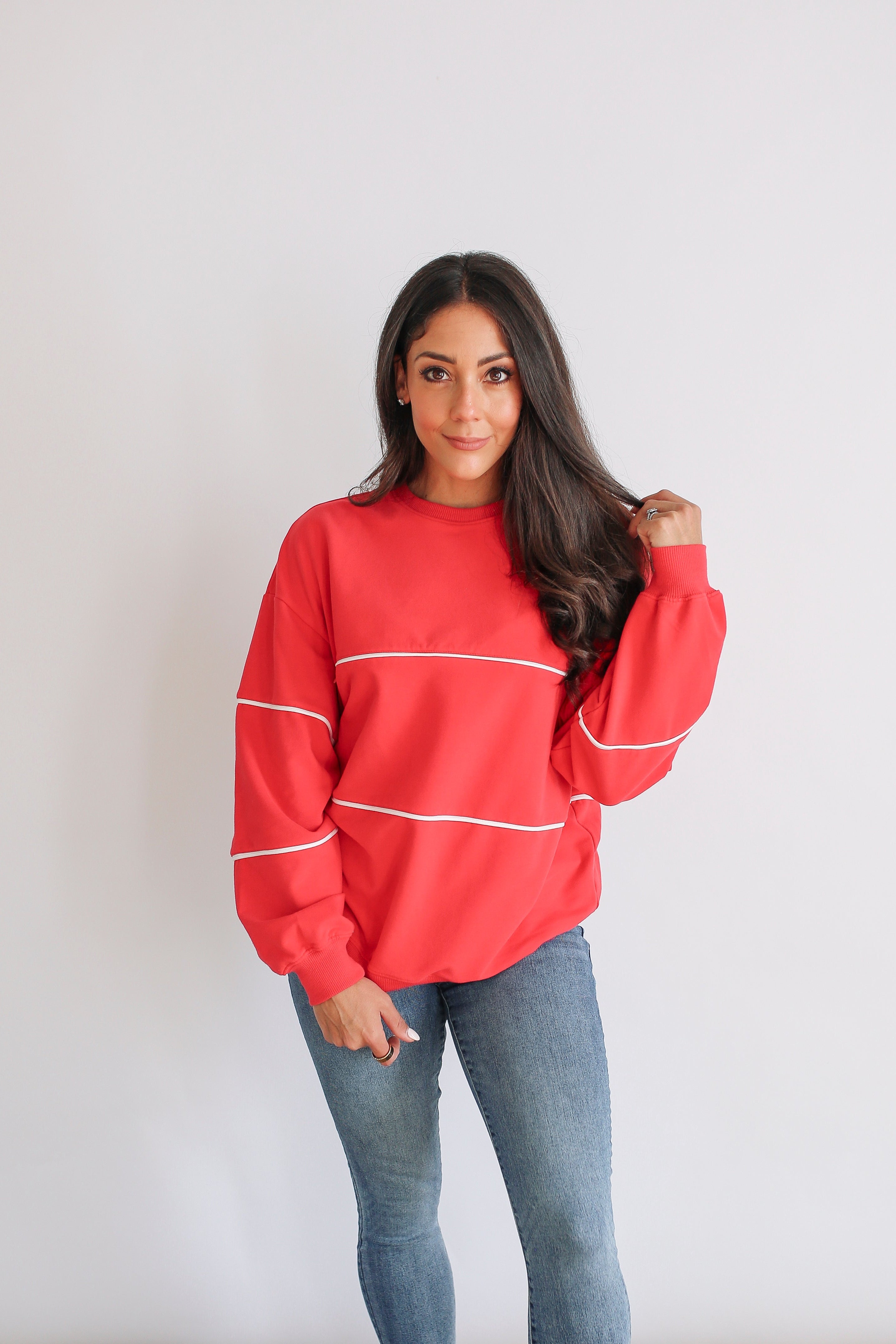 Woman wearing a red breastfeeding sweatshirt with white stripes on a plain background